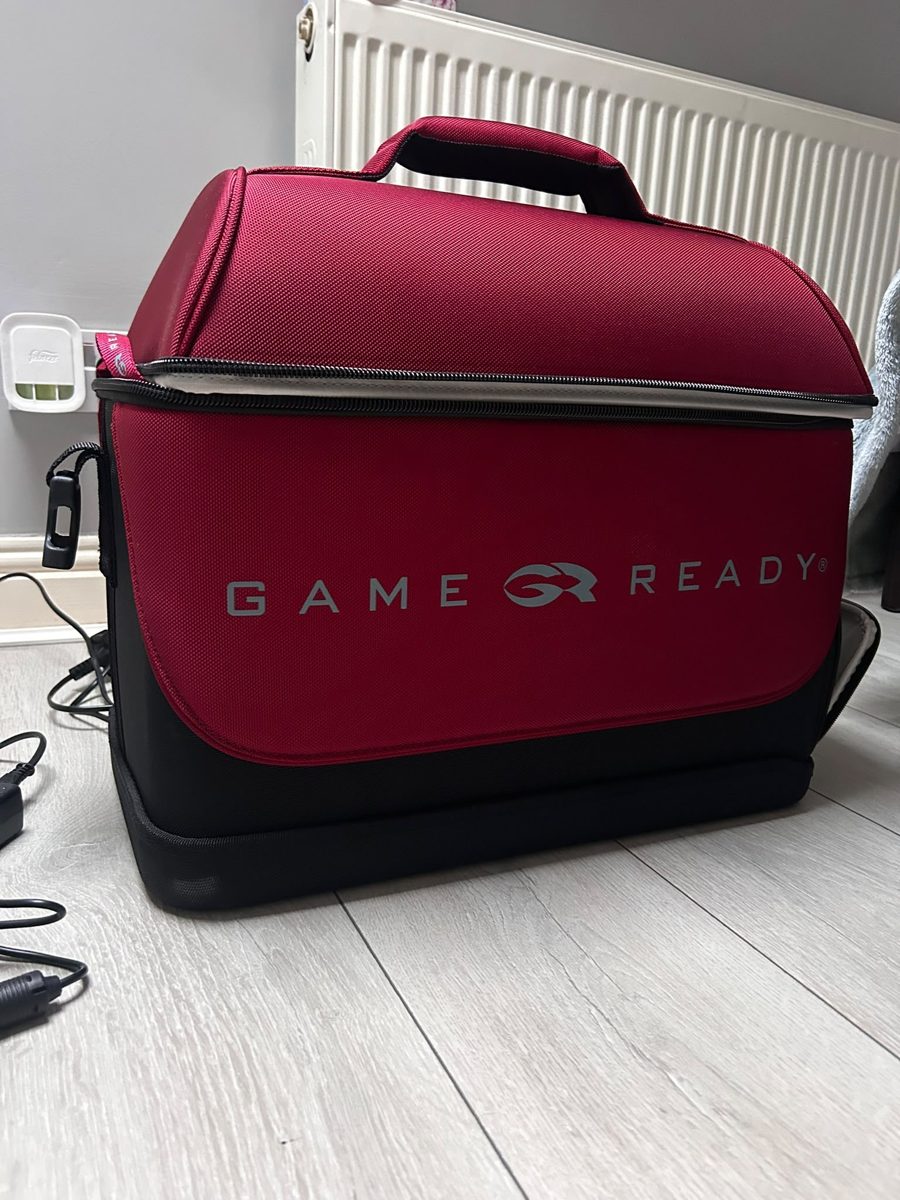 The Game Ready carry bag on the floor at home, with the power cable beside it