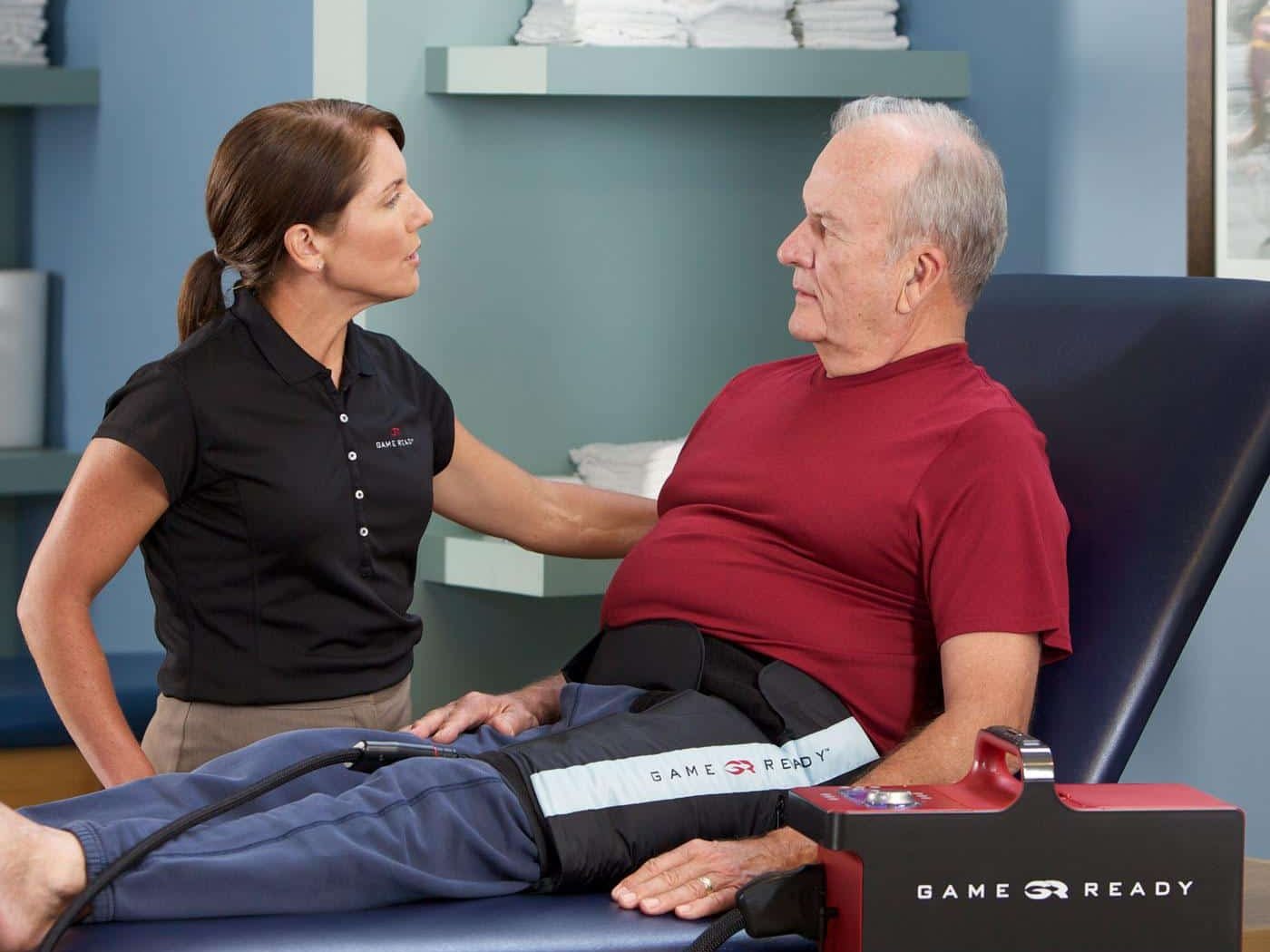 A clinician talking with a patient who is wearing a Game Ready hip wrap connected to the GRPro 2.1 unit