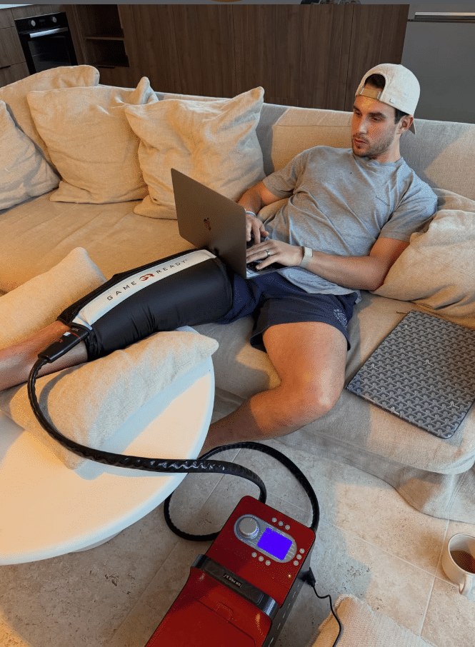 Joey Carbery wearing a Game Ready knee wrap at home, with the Game Ready unit beside him