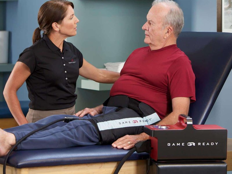 A clinician talking with a patient who is wearing the Game Ready hip and groin wrap